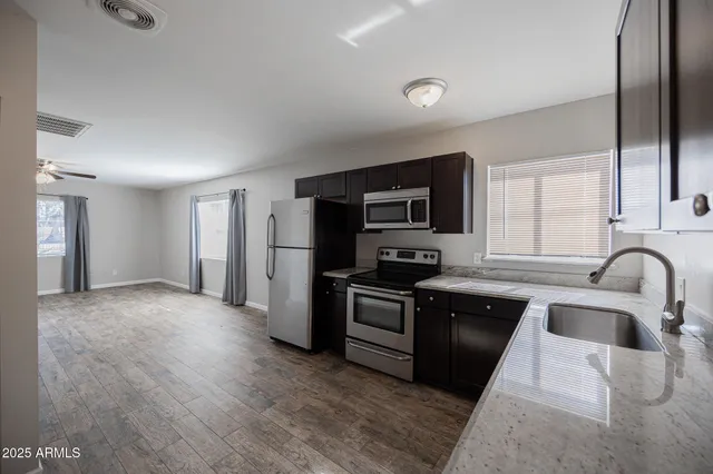 a kitchen with stainless steel appliances granite countertop a refrigerator a sink a stove top oven a counter space and cabinets