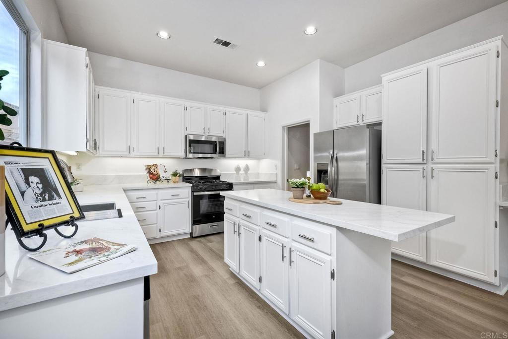 1120 Lassen Peak Place Chula Vista, CA 91913 - Photo 12 of 48 a kitchen with kitchen island white cabinets and refrigerator