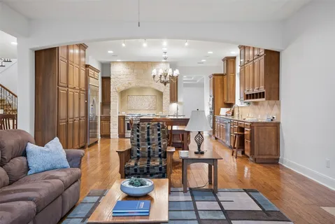 a view of a hallway to a livingroom with wooden floor and furniture