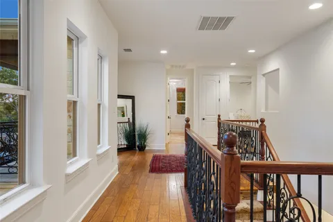 a view of a hallway to a livingroom with wooden floor and furniture
