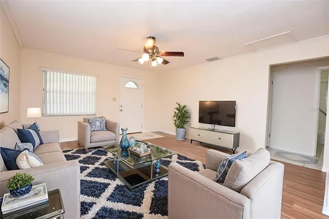 an empty room with wooden floor chandelier fan and windows