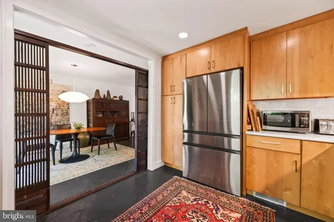 a kitchen with stainless steel appliances granite countertop a refrigerator a stove and a dining table with wooden floor