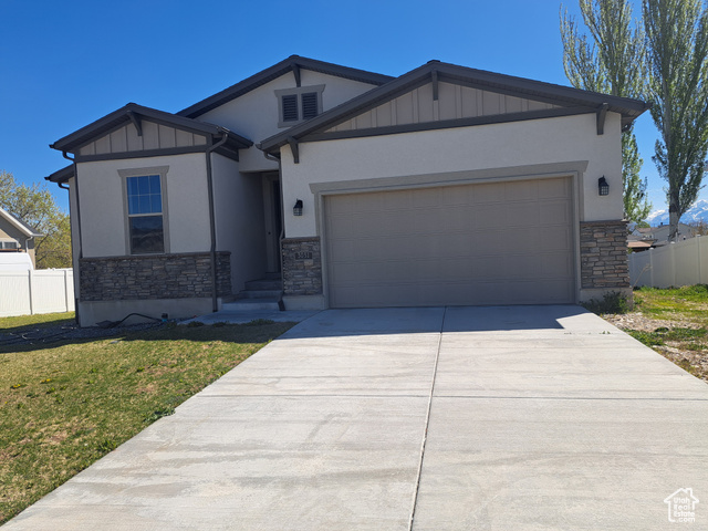 Craftsman inspired home featuring board and batten siding, stone siding, and fence