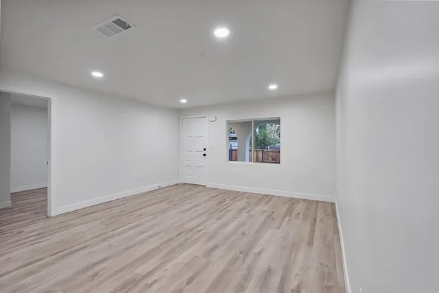 an empty room with wooden floor and windows