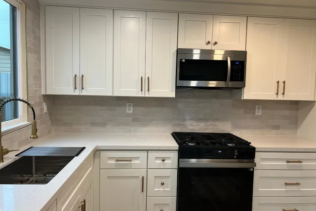 a kitchen with granite countertop white cabinets and black appliances