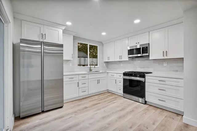a kitchen with stainless steel appliances granite countertop a refrigerator stove and sink