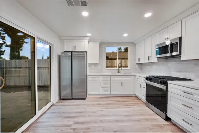 a kitchen with stainless steel appliances granite countertop a refrigerator and a stove top oven