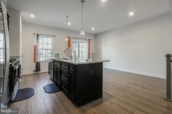 a kitchen with stainless steel appliances granite countertop a sink cabinets and wooden floor