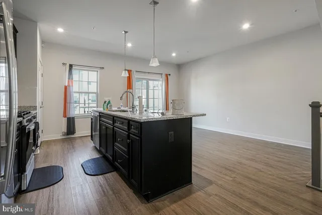 a kitchen with stainless steel appliances granite countertop a sink cabinets and wooden floor