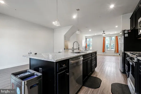 a kitchen with granite countertop a sink a counter top space stainless steel appliances and cabinets
