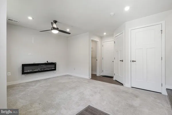 an empty room with chandelier fan and windows