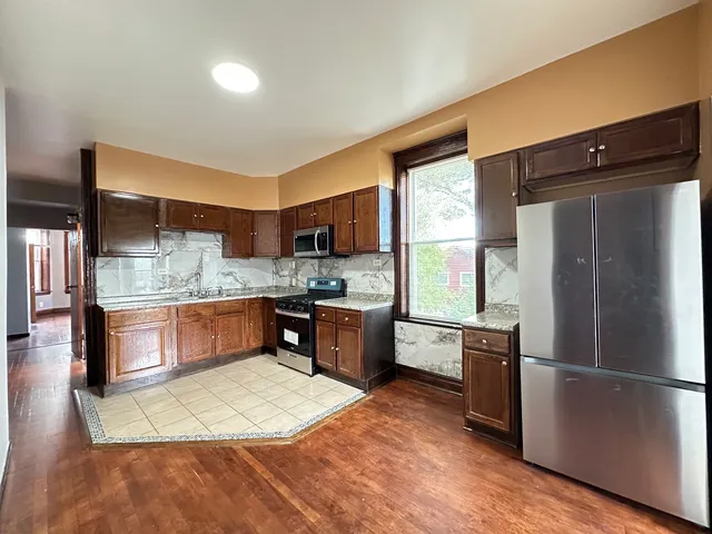 a large kitchen with a large counter top space a refrigerator a sink a stove a microwave and cabinets