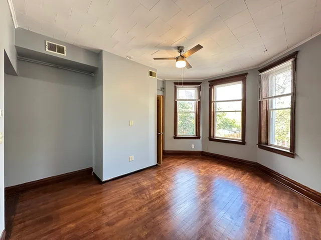 a view of an empty room with a window and wooden floor