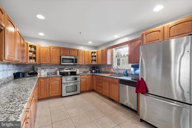 a large kitchen with stainless steel appliances granite countertop a refrigerator oven a sink dishwasher and a refrigerator