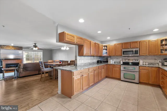 a kitchen with stainless steel appliances granite countertop a stove top oven a sink dishwasher a dining table and chairs with wooden floor