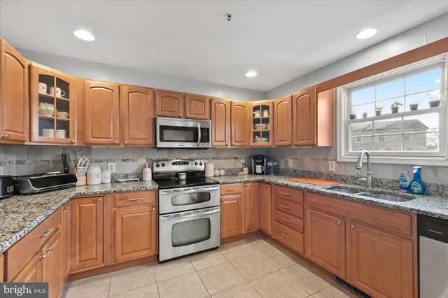 a kitchen with stainless steel appliances granite countertop white cabinets sink stove and microwave