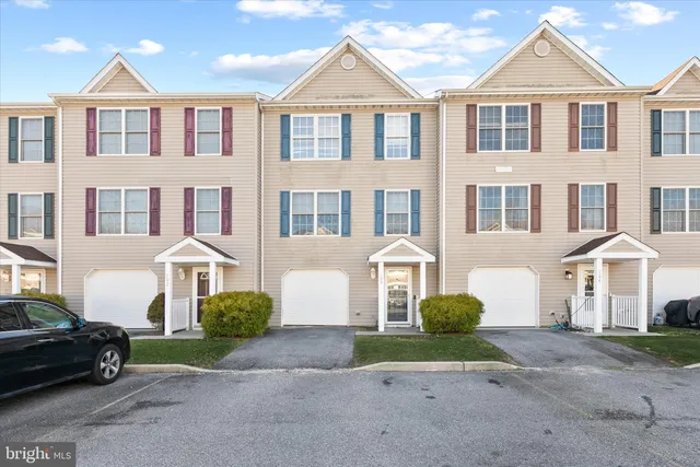 a front view of a house with a yard and parking