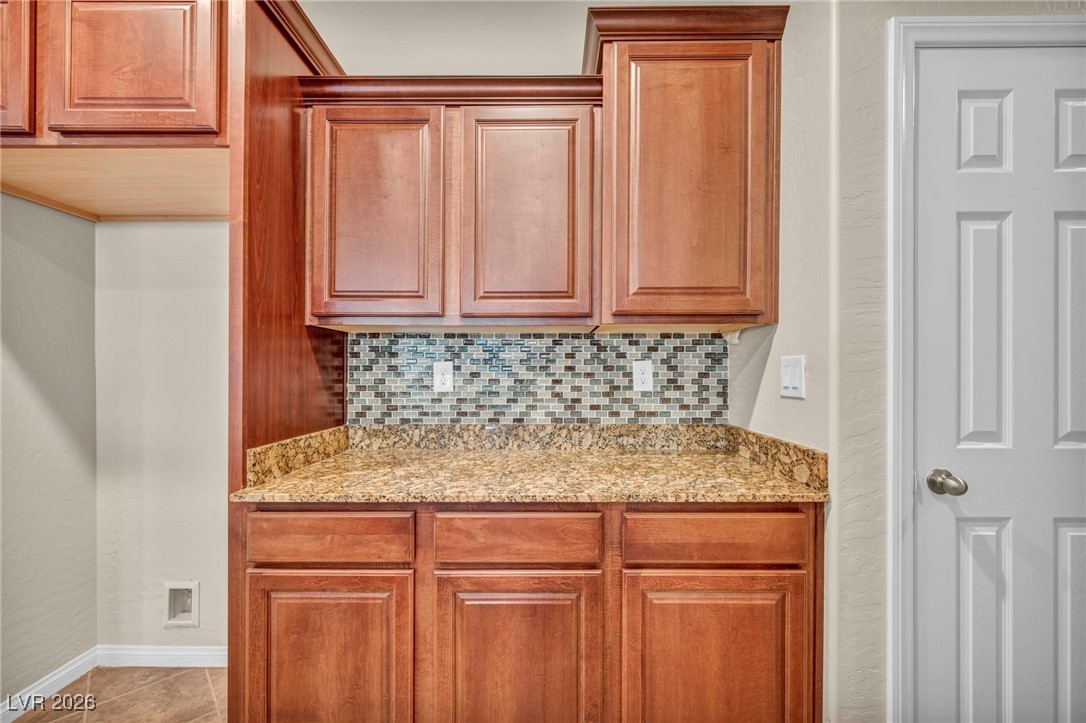 356 Aqua Springs Road Las Vegas, NV 89148 - Photo 15 of 39 Kitchen featuring light stone countertops, tasteful backsplash, and brown cabinets