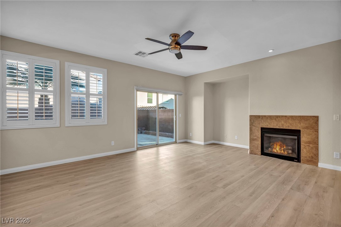 356 Aqua Springs Road Las Vegas, NV 89148 - Photo 20 of 39 Unfurnished living room with light wood finished floors, ceiling fan, and a fireplace