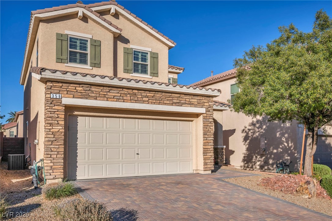 356 Aqua Springs Road Las Vegas, NV 89148 - Photo 2 of 39 Mediterranean / spanish-style house with stone siding, stucco siding, decorative driveway, a tile roof, and an attached garage