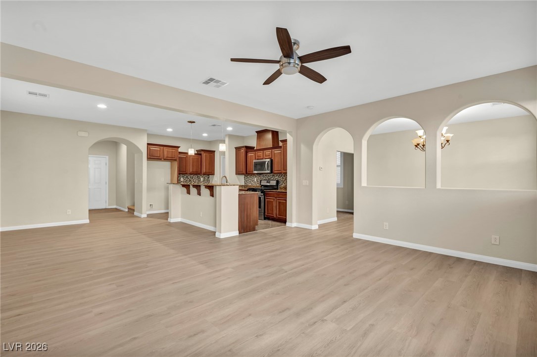 356 Aqua Springs Road Las Vegas, NV 89148 - Photo 5 of 39 Unfurnished living room featuring arched walkways, a chandelier, recessed lighting, light wood-style floors, and ceiling fan