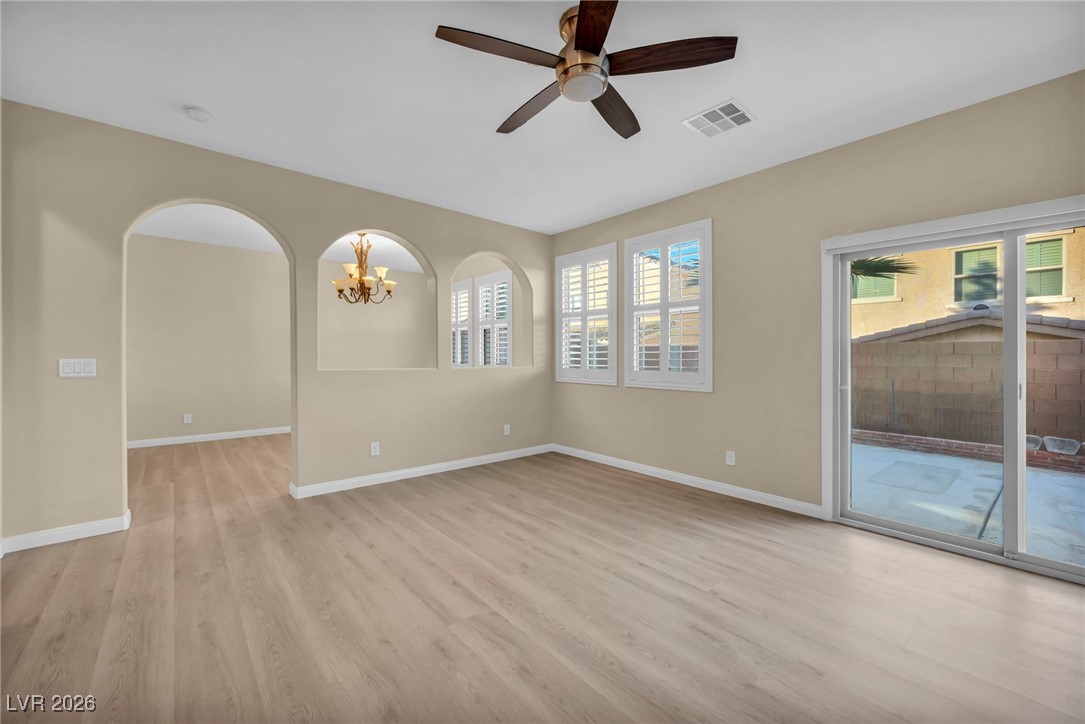 356 Aqua Springs Road Las Vegas, NV 89148 - Photo 6 of 39 Spare room featuring light wood-style flooring, a chandelier, ceiling fan, and arched walkways