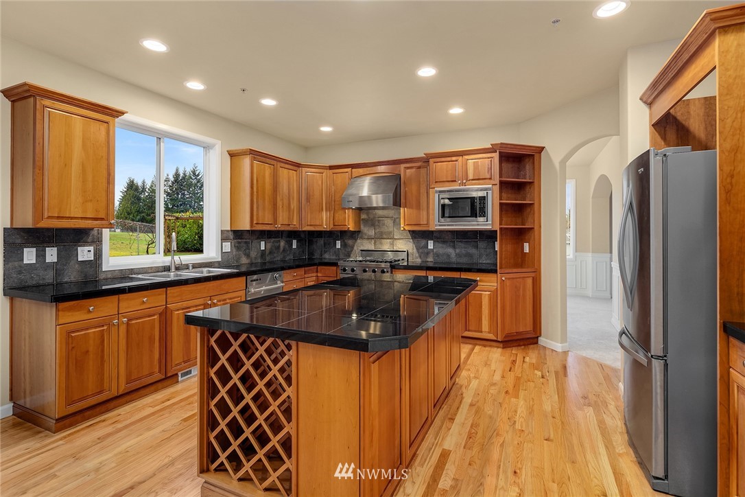 4209 Northeast 27th Place Renton, WA 98059 - Photo 14 of 35 a kitchen with stainless steel appliances granite countertop a refrigerator a sink dishwasher a stove and a dining table with wooden floor