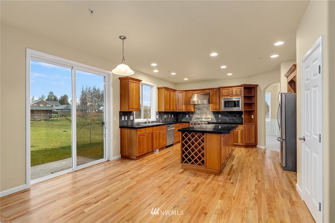 4209 Northeast 27th Place Renton, WA 98059 - Photo 16 of 35 a open kitchen with stainless steel appliances granite countertop a refrigerator a sink dishwasher a stove and a dining table with wooden floor