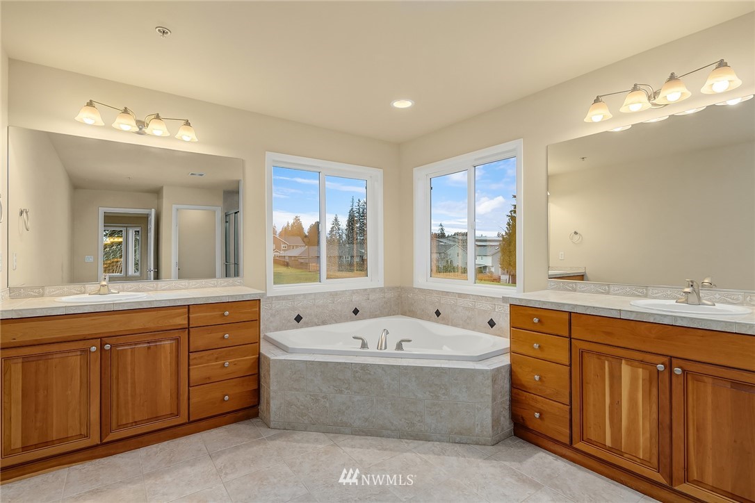 4209 Northeast 27th Place Renton, WA 98059 - Photo 25 of 35 a bathroom with a tub a sink double vanity granite and a mirror