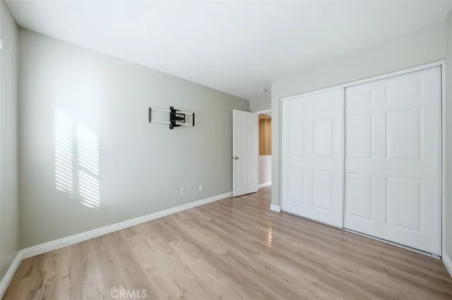 an empty room with wooden floor closet and windows