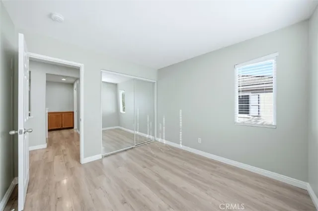 a view of an empty room with wooden floor and closet