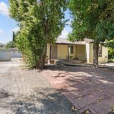 a view of a house with a yard and large tree