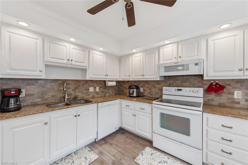 a kitchen with granite countertop white cabinets white stainless steel appliances and sink