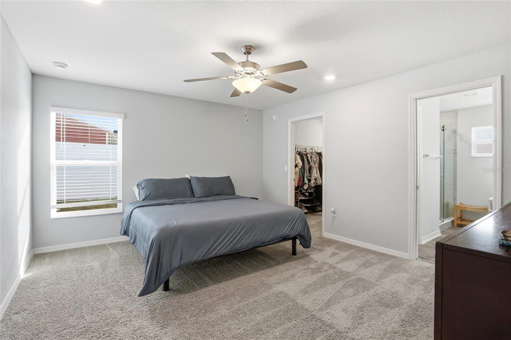 128 Foxtail Loop Davenport, FL 33837 - Photo 11 of 37 a bedroom with a bed and a chandelier
