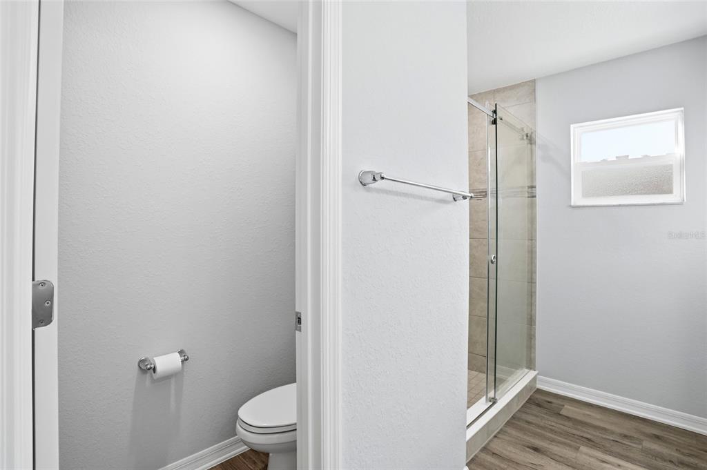 128 Foxtail Loop Davenport, FL 33837 - Photo 15 of 37 a bathroom with a granite countertop toilet a sink and a mirror