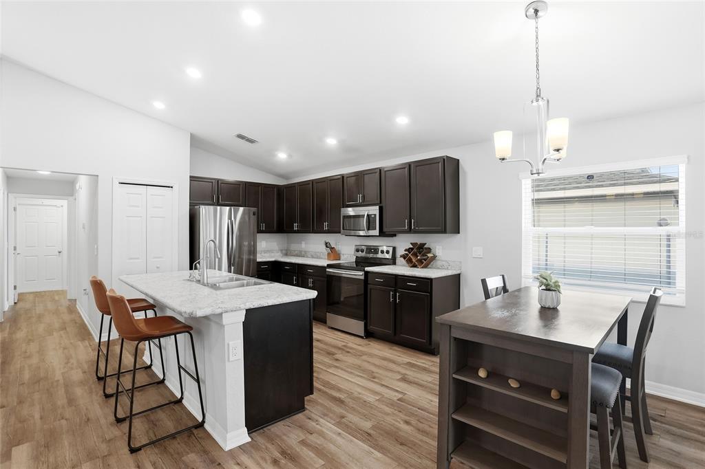 128 Foxtail Loop Davenport, FL 33837 - Photo 17 of 37 a kitchen with a stove a refrigerator and a dining table