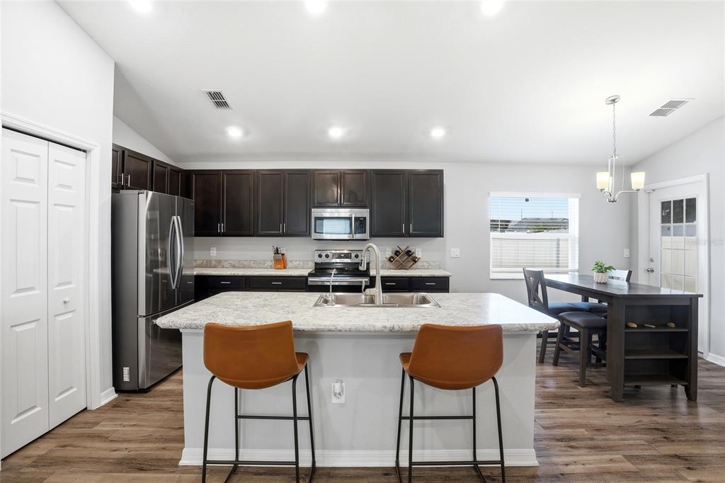 128 Foxtail Loop Davenport, FL 33837 - Photo 18 of 37 a kitchen with stainless steel appliances granite countertop a stove a refrigerator a kitchen island a table and chairs