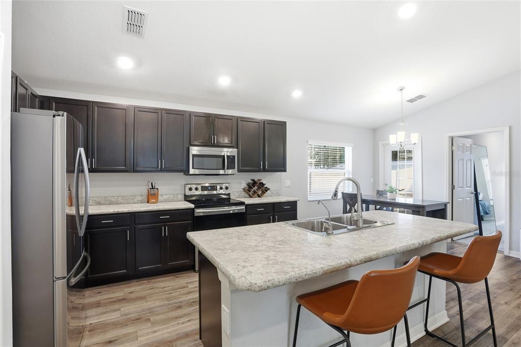 128 Foxtail Loop Davenport, FL 33837 - Photo 19 of 37 a kitchen with stainless steel appliances granite countertop a table chairs sink refrigerator and microwave