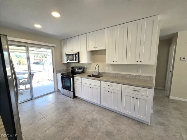 a kitchen with granite countertop a refrigerator sink and cabinets