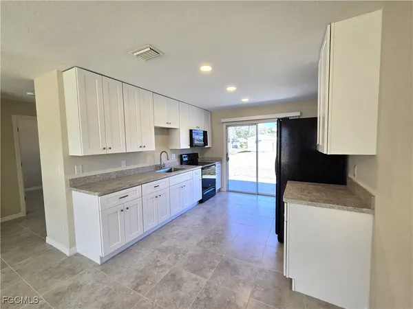 a kitchen with granite countertop white cabinets and stainless steel appliances