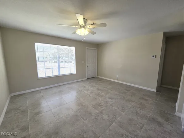 an empty room with chandelier fan and windows