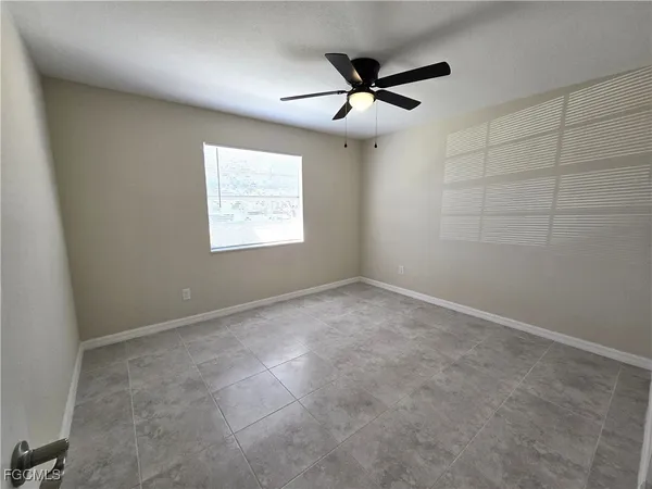 an empty room with a window and a fan