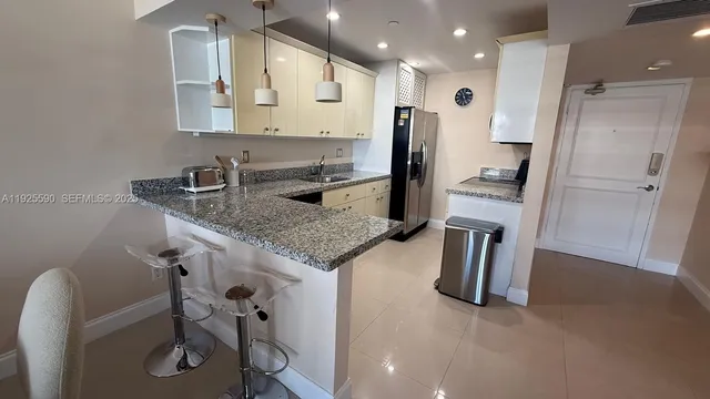 a kitchen with refrigerator and chairs