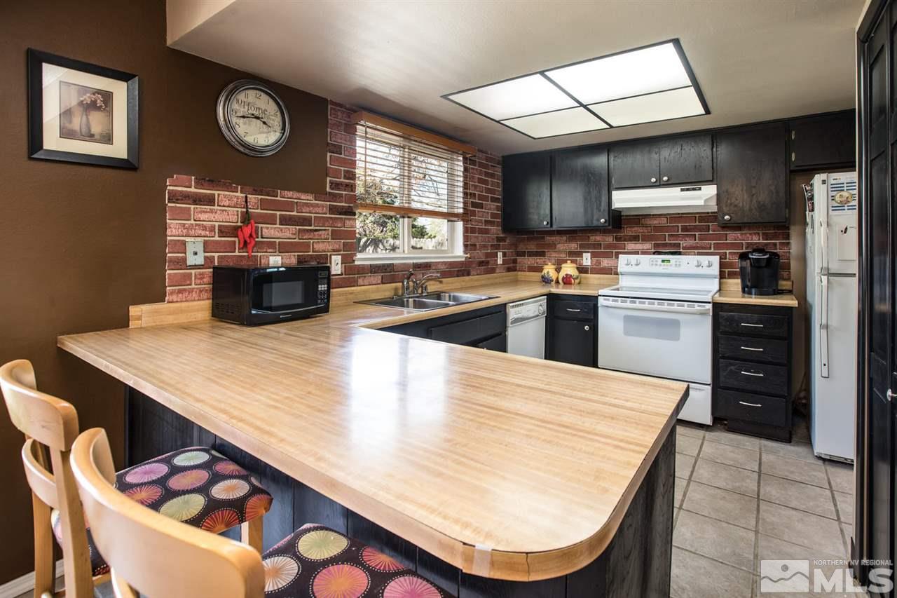 1845 Kings Row Reno, NV 89503 - Photo 7 of 25 a kitchen with stainless steel appliances granite countertop a stove a refrigerator a oven a sink a dining table and chairs