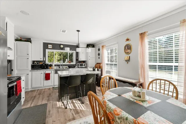 a kitchen with stainless steel appliances kitchen island granite countertop a table chairs sink and window