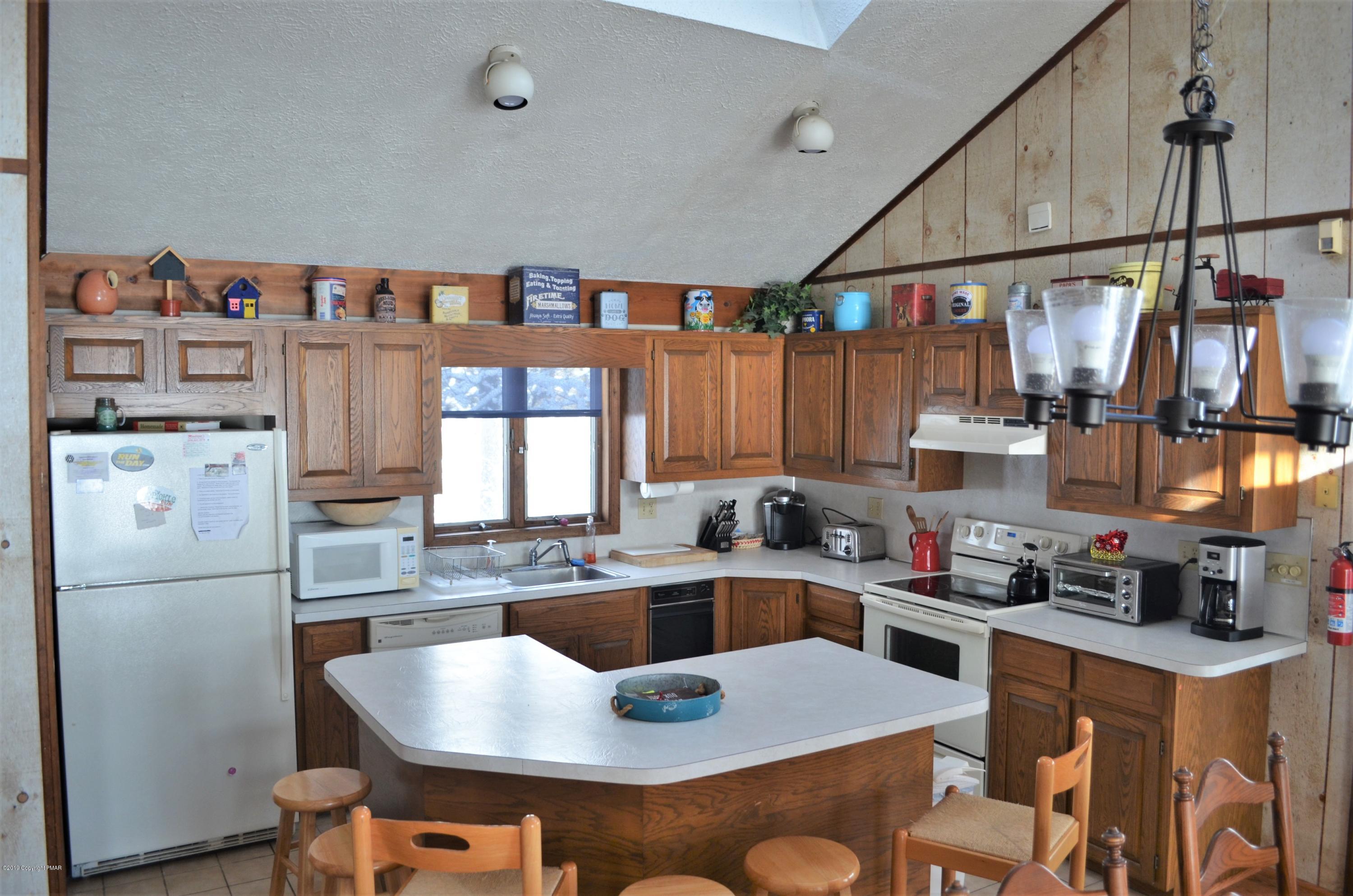9 Birch Point Road Gouldsboro, PA 18424 - Photo 10 of 41 a kitchen with stainless steel appliances granite countertop a sink dishwasher a refrigerator a microwave oven and a dining table with wooden floor