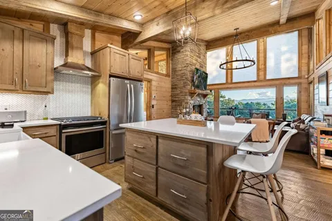 a kitchen with stainless steel appliances granite countertop a refrigerator a sink dishwasher a dining table and chairs with wooden floor