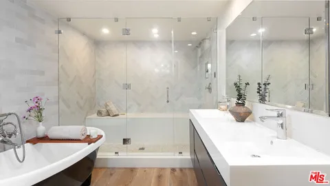 a bathroom with a tub a sink a potted plant and a shower