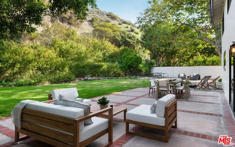 a view of a patio with table and chairs potted plants and a large tree
