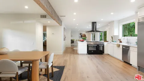 a kitchen with stainless steel appliances a sink a stove a refrigerator cabinets and wooden floor